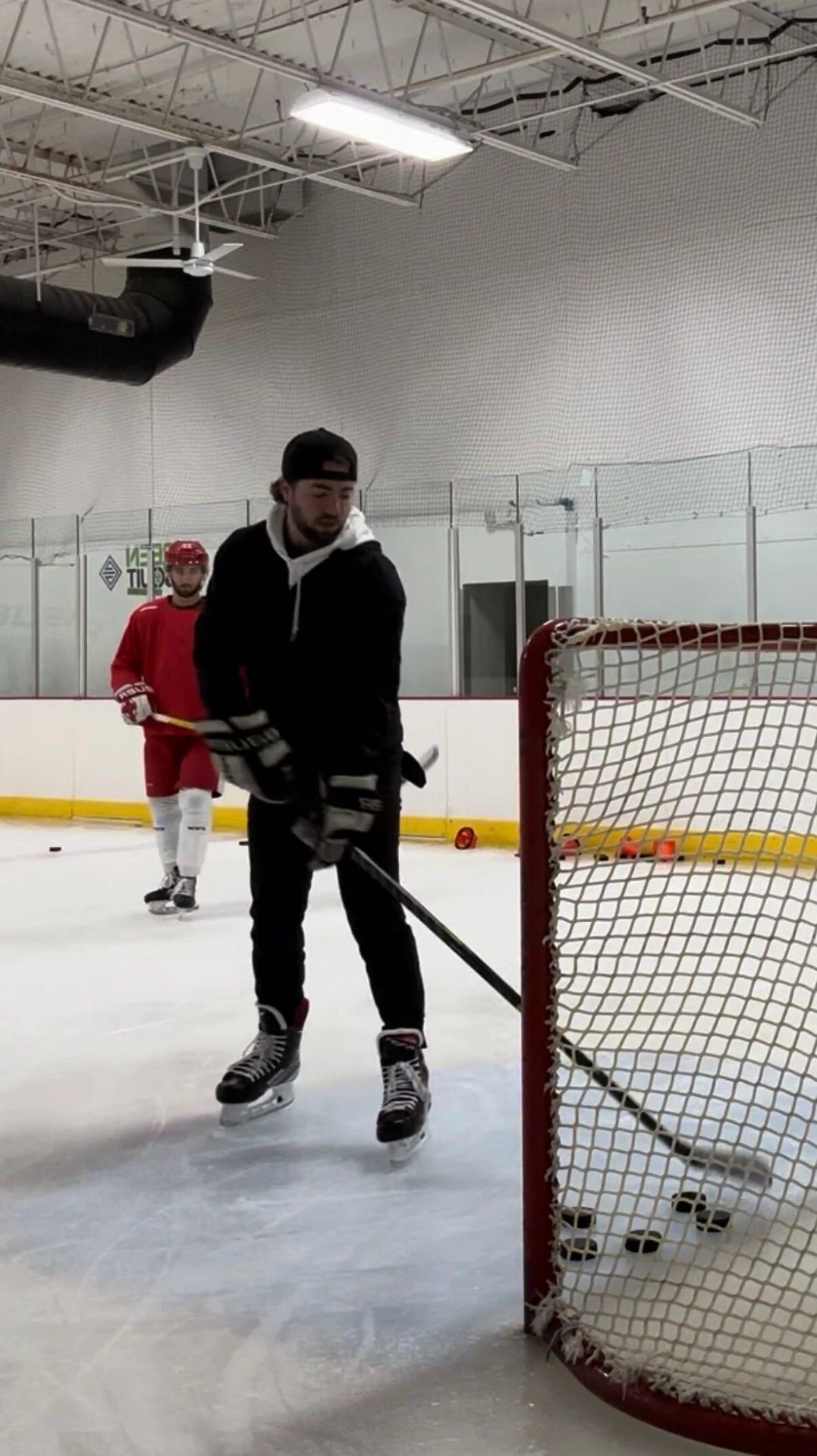 An Overload Hockey coach working with a player at the goal line during an on-ice session